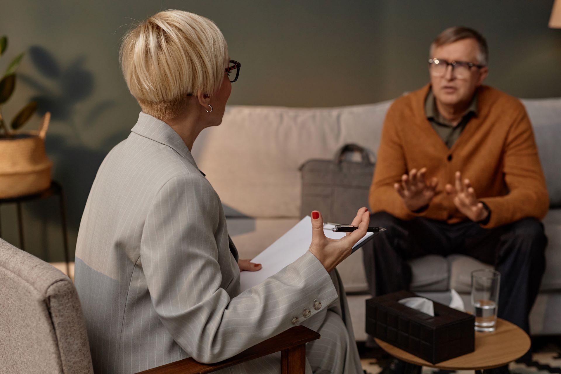 A licensed therapist with a notepad listening to a client during a psychotherapy session.