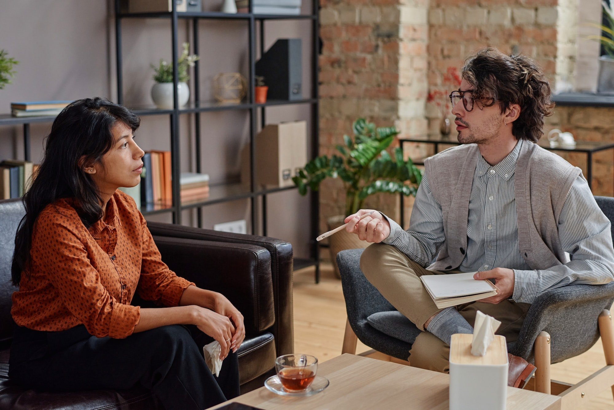 A therapist and client sitting across from each other in conversation during a therapy session.